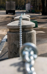 concrete fence in the form of concrete bollards with a chain along the sidewalk in the city