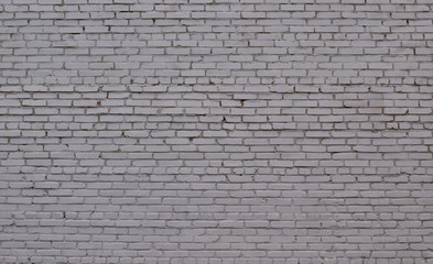 Fototapeta na wymiar Ordered texture of a nervous brick wall of an old building painted with white paint