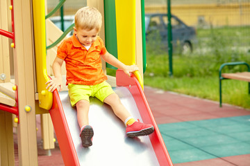 Fototapeta na wymiar active little boy on slide on playground
