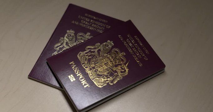 Two UK Passports on a desktop.  Space for text overlays. FS7 4K.