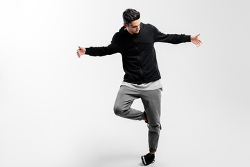 Stylish young dancer wearing a black sweatshirt and gray pants is dancing hip-poh