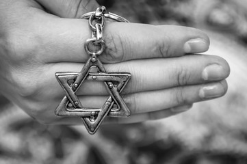 A hand of a young woman holding a key chain with a Star of David, traditional Jewish symbol. A...