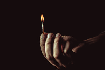 Burning match in the man's hand. Dangerous game with fire.