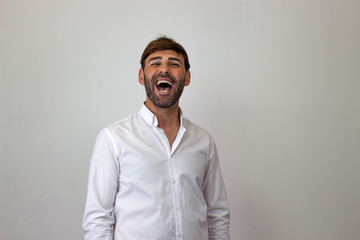Obraz premium Fashion portrait of handsome young man with brown hair laughing, their back facing the camera and looking at the camera. Isolated on white background.