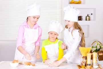 Portrait of three cute girls cooking on kitchen