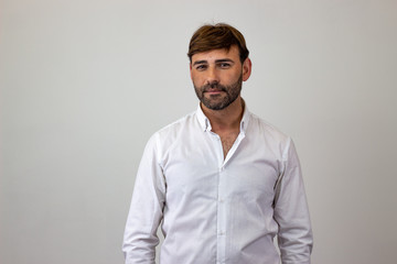 Obraz premium Moda piękny portret przystojny młody mężczyzna z brązowymi włosami w miłości, patrząc w kamerę. Na białym tle