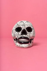 White skull, mexican crafts over pink background