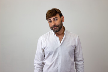 Fashion portrait of handsome young man with brown hair and a look of disgust, looking at the camera. Isolated on white background.