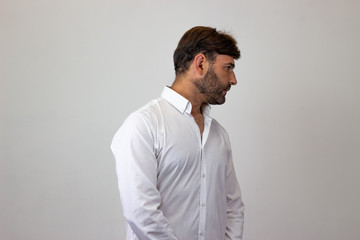 Fashion portrait of handsome young man with brown hair and a look of disgust, facing forwards and...