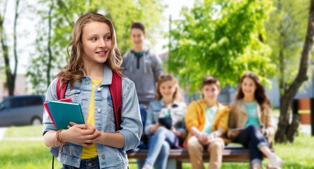 education, school and people concept - happy smiling teenage student girl with bag and books over group of friends background