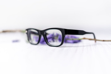 lentes de pasta negros sobre fondo blanco y flores purpuras