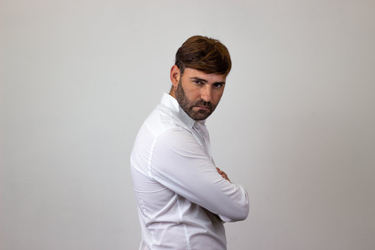 Fashion Portrait Of Handsome Young Man With Brown Hair Looking Annoyed, Their Back Facing The Camera And Looking At The Camera. Isolated On White Background.