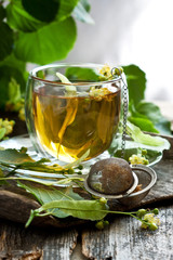 Cup of linden tea and  flowers on  wooden table