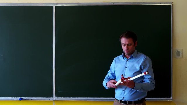 Math teacher drawing a circle with a compass on a blackboard in a classroom.
