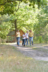 Obraz premium Portrait of happy family of four in autumn park running