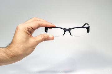 A male hand holding a half frame eyeglasses isolated over white.