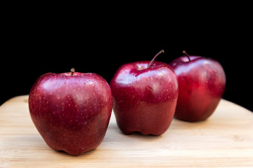 Three healthy and organic red apples on black background.