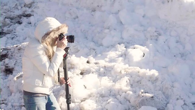 Female photographer using a monopod and taking images within a snowy scene.