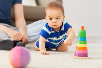 family, fatherhood and childhood concept - happy baby boy with father and toy pyramid at home