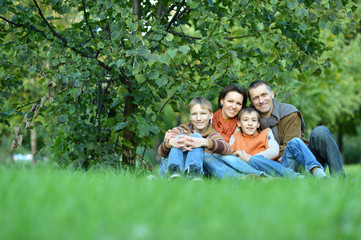Fototapeta premium Family of four posing sitting on grass
