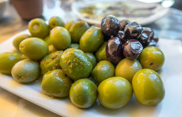 Spiced olives in a small plate on the tapas bar table a typical Spanish black and green split olive.