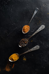 Various colorful spices on black background, top view.