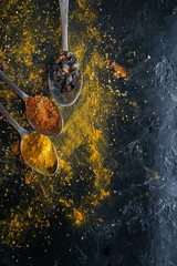 Various colorful spices on black background, top view.