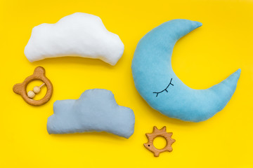 Moon pillow, clouds and toys for put baby in bed on yellow background top view