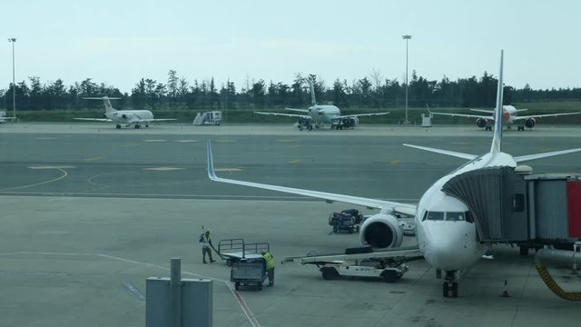 Airport Staff putting Baggage on the Conveyor Belt of Airplane. Luggage is loaded on a passenger plane by aiport workers