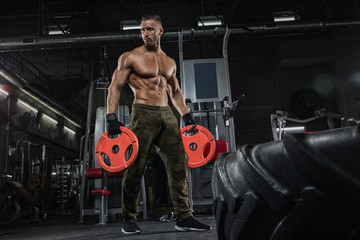 Naklejka premium Young handsome sportsman bodybuilder weightlifter with an ideal body