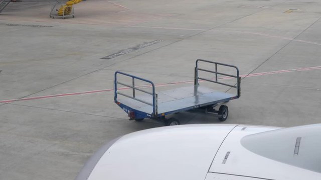 Empty baggage cart in the aiport. View from the plane through the window