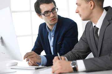 Businessmen working with computer in modern office. Headshot of male entrepreneur or company manager at workplace. Partners discussing contract. Business concept