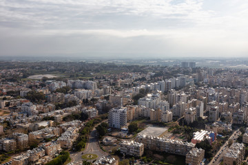 Fototapeta na wymiar Aerial view of a residential neighborhood in a city during a cloudy and sunny sunrise. Taken in Netanya, Center District, Israel.