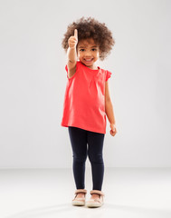 childhood, gesture and people concept - happy little african american girl showing thumbs up over...