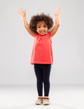 childhood and people concept - happy little african american girl with hands up over grey background