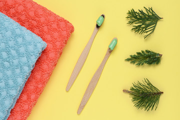 Bamboo toothbrushes with natural toothpaste on yellow background top view