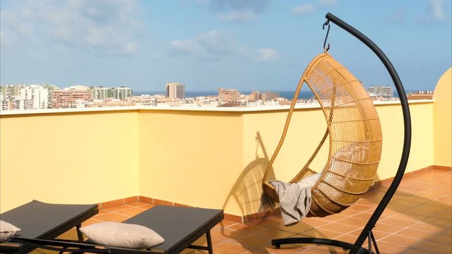 Hanging chair and sun beds in a sunny terrace of a relaxing summer holiday destination with sea view.
