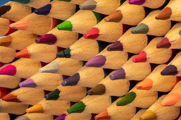 Colored pencils with sharpened points lined in rows.