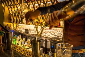 Barman preparing and serving cocktails. Picture with blurry bar environment in the background.