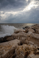 Beautiful view on the rocky and muddy coast near the Old City of Akko during a cloudy and sunny day. Taken in Acre, Israel.