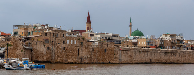 Fototapeta premium Beautiful Panoramic view of the Old City of Akko on the coast of Mediterranean Sea during a cloudy and sunny day. Taken in Acre, Israel.