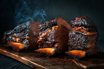 Cut a large piece of smoked beef brisket to the ribs with a dark crust. Classic Texas barbecue - obrazy, fototapety, plakaty