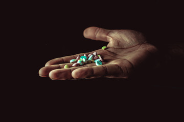 pills in hand on black background