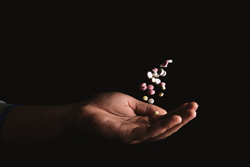 pills in hand on black background