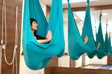Woman meditation in hammock. fly yoga stretching exercises in gym. Fit and wellness lifestyle