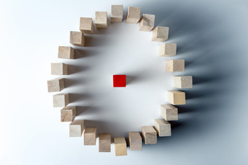 a large circle of wooden cubes, one red in the center, as a symbol of the assembly, a number of tasks and a leader, on an uneven white background. Horizontal frame