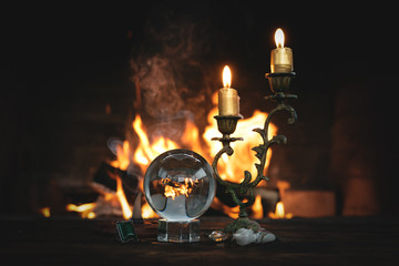 Crystal ball on the magic table on a burning fire background. Future reading.