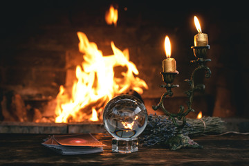 Tarot cards and crystal ball on fortune teller table on a burning fire background. Futune reading concept. Divination.