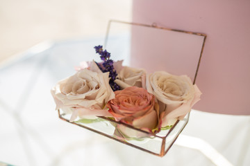 closeup glass box for wedding rings decorated with fresh rose flowers and banch of lavender. Event decoration with fresh flowers