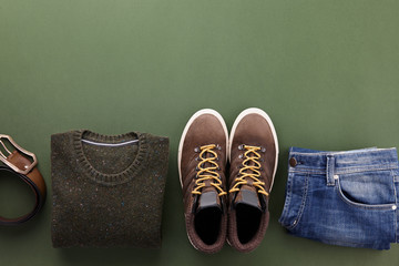 Mens casual clothing outfits and accessories flat lay on olive green background, top view